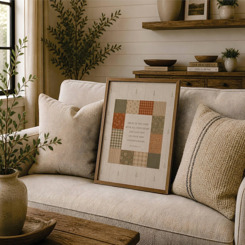 May include: A framed wall art piece featuring a central square with a patchwork quilt design in muted green, orange, and cream tones. The center contains the text: Trust in the Lord with all your heart and lean not on your own understanding.