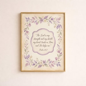 May include: A rectangular wall art print in a gold frame featuring a watercolor floral wreath in shades of purple, lavender, and green. The center contains the text: The Lord is my strength and my shield; my heart trusts in Him, and He helps me. Psalm 28:7.