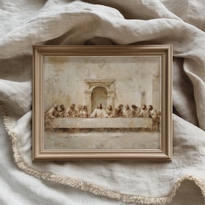 May include: A rectangular wall art print featuring a neutral-toned depiction of The Last Supper, encased in a light-colored wooden frame. The artwork displays a central figure seated at a long table surrounded by twelve individuals in a stone room.