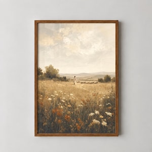 Può includere: Una stampa d'arte incorniciata raffigurante un paesaggio dipinto con una figura in veste bianca che cammina attraverso un campo dorato di fiori selvatici verso un gregge di pecore in lontananza sotto un cielo nuvoloso dai toni terra e cornice marrone.