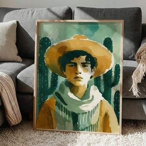 Könnte beinhalten: Aquarellmalerei einer Person mit gelbem Hut und Schal, mit Kaktushintergrund. Das Kunstwerk ist in einem hellen Holzrahmen gerahmt. Die Person hat dunkles Haar und trägt ein gelbes Hemd.