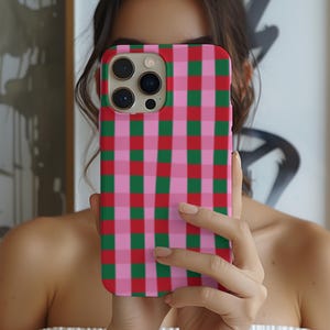 May include: A rectangular smartphone case featuring a vibrant plaid pattern of intersecting vertical and horizontal stripes in shades of bright red, forest green, and light pink. The case includes a square cutout for the camera lens array.