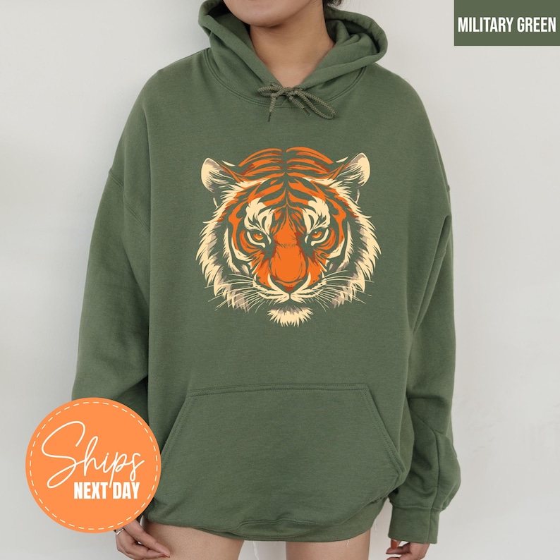 A person wearing a green hoodie with a graphic of a tiger's face printed on it.