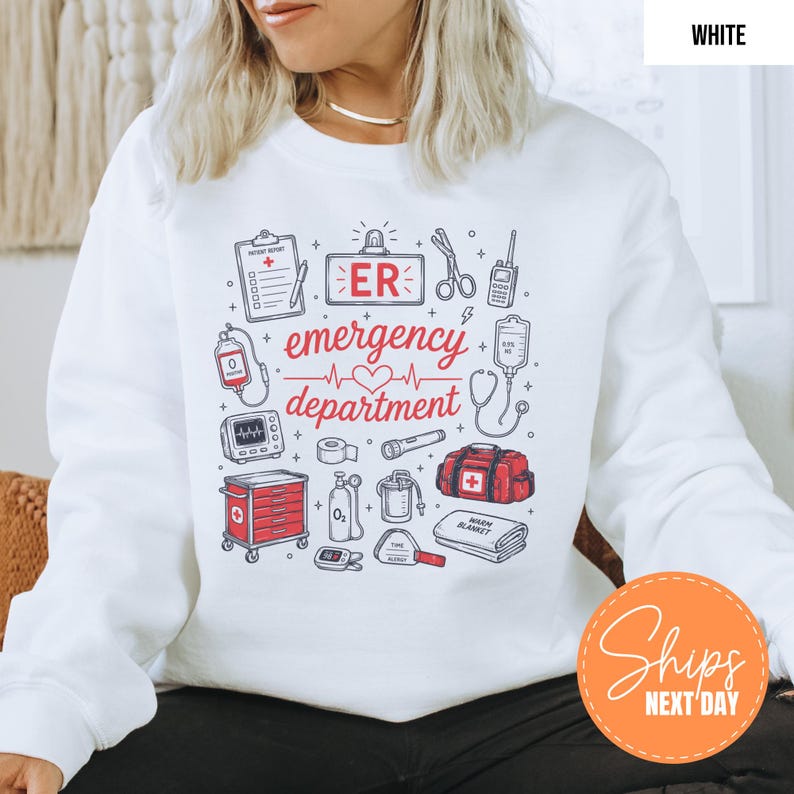 May include: A white long-sleeve sweatshirt featuring a graphic print of medical equipment and the text "ER emergency department". The design includes illustrations of a clipboard, scissors, radio, IV bag, heart monitor, oxygen tank, and medical bag.