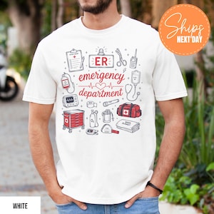 Puede incluir: Una camiseta blanca con un estampado gr&aacute;fico que incluye el texto "ER emergency department" en rojo, rodeado de ilustraciones de l&iacute;nea en negro y rojo de equipos m&eacute;dicos, como un portapapeles, un estetoscopio, un tanque de ox&iacute;geno y un malet&iacute;n m&eacute;dico.