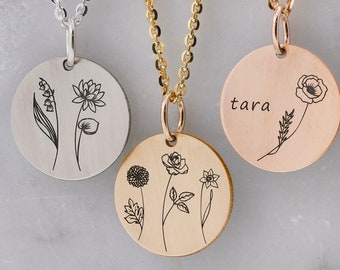 Op de afbeelding: Drie kettingen van zilver, goud en roségoud met ronde hangers met gegraveerde bloemenmotieven. De zilveren hanger heeft een lelietje-van-dalen en een lotusbloem. De gouden hanger heeft een roos, een dahlia en een narcis. De roségouden hanger heeft een klaproos en het woord "tara" is erop gegraveerd.