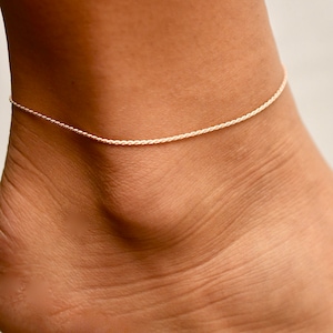 May include: A delicate silver chain anklet on a person's ankle.