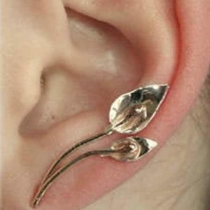 May include: Gold leaf ear cuff with two leaves, one slightly larger than the other, attached to a thin wire.