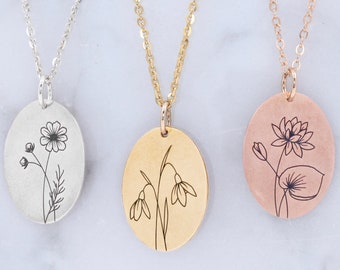 Op de afbeelding: Drie delicate kettingen met ovale hangers met gegraveerde bloemenmotieven. De hangers zijn zilver, goud en roségoud, elk met een ander bloemendesign.