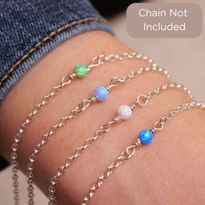 May include: Four silver chain bracelets with different colored opal beads. The beads are green, blue, white, and light blue. The text "Chain Not Included" is visible in the image.