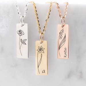 Peut inclure: Trois colliers en argent, or et or rose avec des pendentifs rectangulaires ornés de motifs floraux gravés. Le pendentif en argent a une rose, le pendentif en or a une jonquille et le pendentif en or rose a du muguet avec le nom "Katte" gravé dessus.