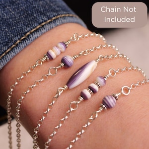 May include: Four bracelets with purple and white shell beads and silver chain.  Chain not included.