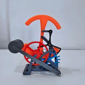 May include: A 3D-printed kinetic sculpture with a complex gear and lever system. The sculpture is made of red, blue, orange, black, and grey plastic. It features a large orange curved element and a weighted grey cylinder. The design is intricate.