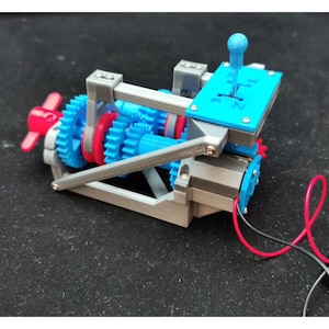 May include: A 3D-printed model of a mechanical device featuring blue and red gears, a blue shift lever, and a gray frame. The model includes a red propeller and is connected by red and black wires. The device is set against a dark background.