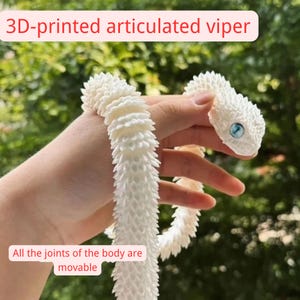 May include: A 3D-printed articulated viper toy in white, with a textured body and blue eyes. The text on the image reads "3D-printed articulated viper" and "All the joints of the body are movable."