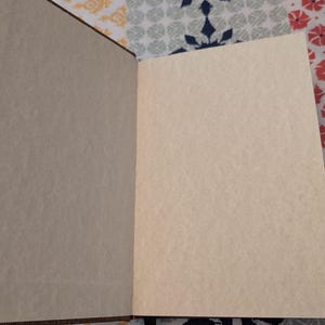 Pu&ograve; includere: Un diario aperto, rilegato in pelle marrone, con pagine bianche color crema. Il diario &egrave; aperto su una superficie a fantasia con un segnalibro a nastro nero. Le pagine sono pronte per scrivere o disegnare.