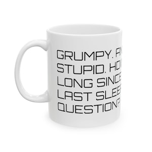 May include: White ceramic mug with a curved handle. The mug features black text that reads: "GRUMPY. AND STUPID. HOW LONG SINCE LAST SLEEP? QUESTION?" A humorous and relatable item for coffee or tea.