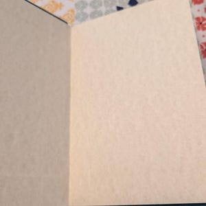 Pu&ograve; includere: Un taccuino aperto con pagine color crema. La copertina del taccuino &egrave; di colore verde scuro. Le pagine sono bianche, pronte per scrivere o disegnare. Il taccuino &egrave; su una superficie a motivi floreali e geometrici.
