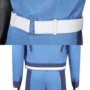 May include: A blue jacket featuring a white belt with a rectangular metal buckle at the waist. The jacket includes dark blue accents along the hem and sleeves, with a horizontal white stripe above the hemline and visible stitching throughout the garment.