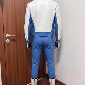 May include: A costume set consisting of a white and blue jacket with a pointed back yoke, matching blue trousers, black gloves, and white mid-calf boots with rear zippers. The ensemble features a color-blocked design with white sleeves and back panel.