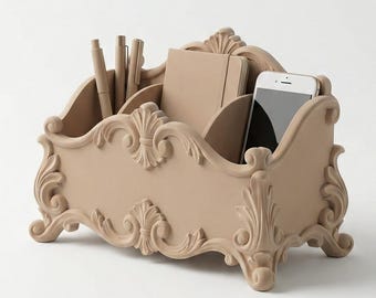 May include: A beige, ornate desk organiser with multiple compartments. It holds pens, a notebook, and a smartphone. The organiser has a decorative, scrolled design and is made of a solid material.