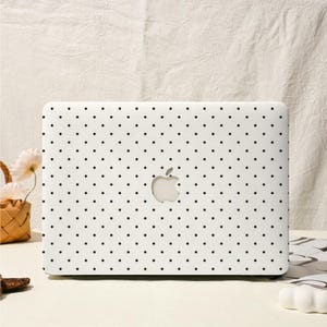 Könnte beinhalten: Ein weißer Laptop mit einem schwarzen Polka-Dot-Muster. Der Laptop hat ein ausgeschnittenes Apple-Logo in der Mitte. Der Laptop steht auf einer weißen Oberfläche.