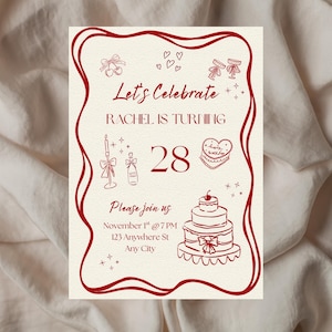 May include: A cream-colored birthday invitation with a burgundy border and illustrations. The text reads "Let's Celebrate, Rachel is turning 28." Includes a cake, champagne, and other celebratory graphics. The invitation also includes the date, time, and location.