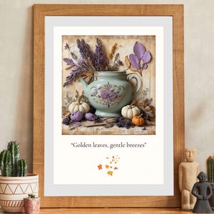 May include: A framed print featuring a teal teapot with purple floral designs, filled with lavender and surrounded by white and orange pumpkins. The text "Golden leaves, gentle breezes" is below the image.