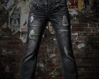 May include: Dark wash denim jeans with distressed details, including rips and fading. The jeans have a button-up fly and a slight flare at the bottom. The background is a brick wall with vintage posters.