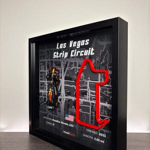 May include: Framed artwork of the Las Vegas Strip Circuit race track. The red track outline is set against a gray map background. The artwork includes the text "Los Vegas Strip Circuit", location, turns, and length of 3.85 mi.