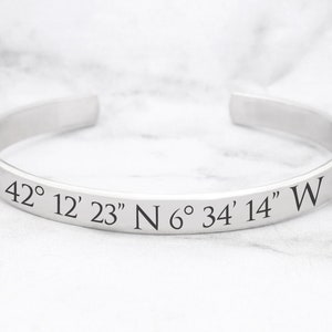 May include: Silver bangle bracelet with engraved coordinates: 42° 12' 23" N 6° 34' 14" W.