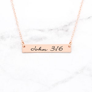 May include: A rose gold necklace with a bar pendant that says "John 3:16" in cursive script.