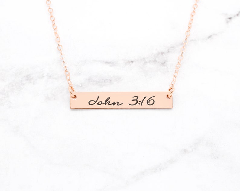 May include: A rose gold necklace with a bar pendant that says "John 3:16" in cursive script.