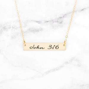 May include: Gold bar necklace with the words "John 3:16" inscribed on it.