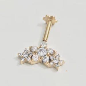Op de afbeelding: Een goudkleurige oorbel in bloemvorm met meerdere heldere, sprankelende edelstenen. De oorbel heeft een lange, dunne pin en een bloemvormige achterkant. Het ontwerp is delicaat en elegant, geschikt voor diverse gelegenheden.