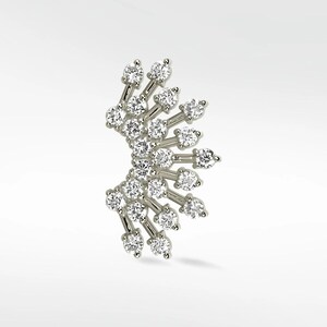 Op de afbeelding: Een zilverkleurige oormanchet met een waaierachtig ontwerp. De manchet is versierd met talrijke ronde, heldere edelstenen, gerangschikt in een stralend patroon. De edelstenen zijn gezet op delicate, rechte staven, wat een sprankelend, elegant accessoire creëert.