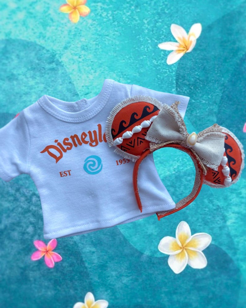 K&ouml;nnte beinhalten: Ein wei&szlig;es T-Shirt mit "Disneyle" in orangefarbener Schrift und einem blauen Wirbellogo, kombiniert mit einem passenden Stirnband. Das Stirnband hat orangefarbene Ohren mit einem Wellenmuster und eine cremefarbene Schleife. Das Stirnband ist rot.