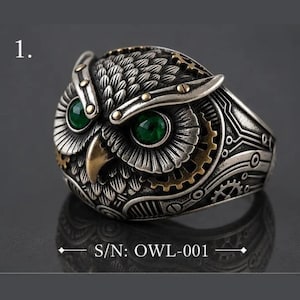 Peut inclure: Une bague argentée en forme de tête de hibou avec deux yeux circulaires vert vif, un bec doré et des détails mécaniques complexes en forme d'engrenages sur les côtés. Le texte S/N: OWL-001 est imprimé au bas du cadre de l'image.