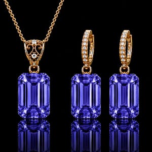 May include: A jewelry set consisting of a necklace and two hoop earrings in gold. Each piece features a large, rectangular, faceted purple gemstone. The necklace pendant has an ornate gold filigree bail, and the hoop earrings are accented with small, clear, round stones along the front edge.
