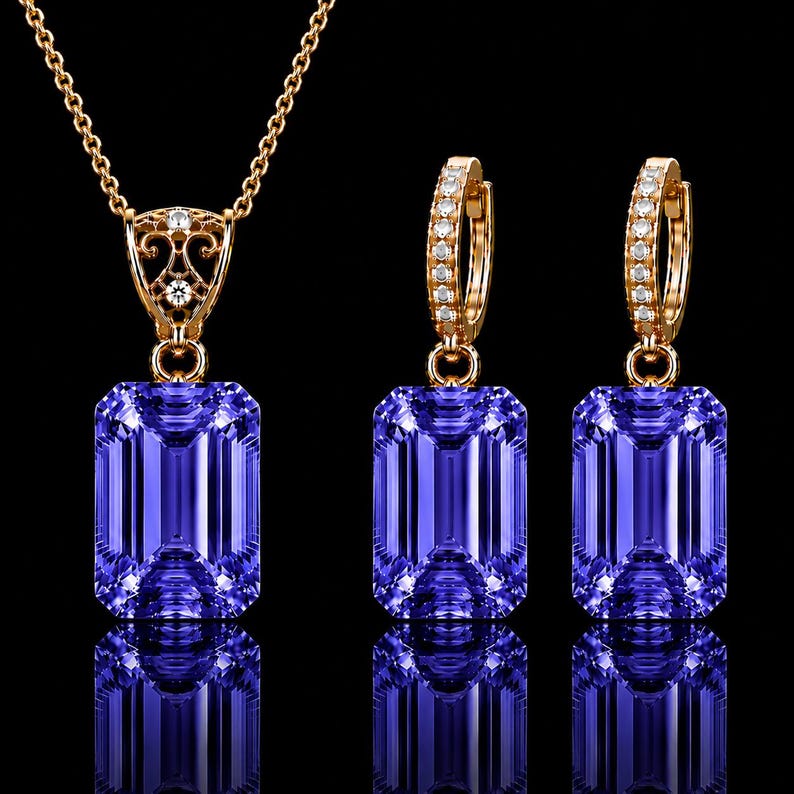 May include: A jewelry set consisting of a necklace and two hoop earrings in gold. Each piece features a large, rectangular, faceted purple gemstone. The necklace pendant has an ornate gold filigree bail, and the hoop earrings are accented with small, clear, round stones along the front edge.