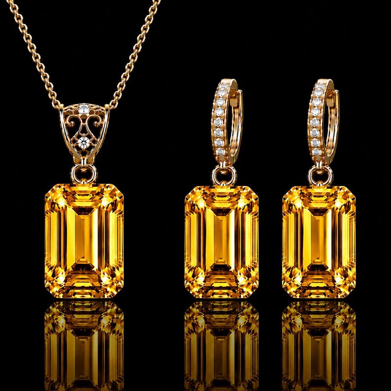 May include: A gold jewelry set consisting of a necklace and two hoop earrings. Each piece features a large, rectangular, emerald-cut yellow gemstone. The necklace pendant and earring hoops are accented with small, clear, round-cut white stones.