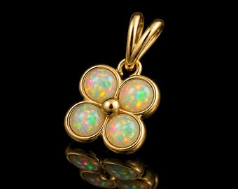 Puede incluir: Un colgante de oro con forma de trébol de cuatro hojas, que presenta cuatro ópalos redondos e iridiscentes engastados en metal dorado pulido. El colgante incluye una anilla dorada en la parte superior para sujetarlo a una cadena, con una superficie.