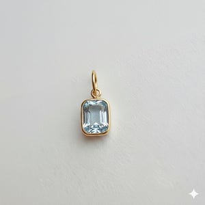 Puede incluir: Colgante rectangular de piedra preciosa azul claro con bisel y fianza dorados. El colgante es de diseño sencillo y elegante, perfecto para el uso diario. La piedra preciosa es de color azul claro.