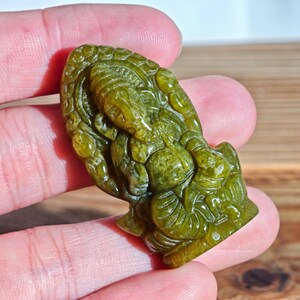 Puede incluir: Una escultura de piedra verde tallada del dios hind&uacute; Ganesha. La escultura est&aacute; detallada con intrincadas tallas y tiene un acabado liso y pulido. La figura est&aacute; representada en posici&oacute;n sentada con m&uacute;ltiples brazos y una cabeza de elefante.