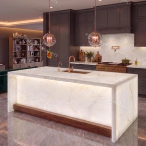 May include: A modern kitchen island with a white marble countertop and a warm wood base. The island features built-in lighting and a gold-toned faucet. The kitchen has dark gray cabinets and pendant lights.