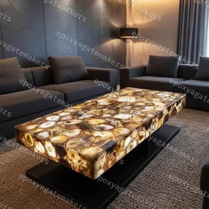 Puede incluir: Una mesa de centro rectangular con una tapa de piedra de ágata. La mesa tiene una base negra y una superficie compuesta por rodajas de ágata marrón, beige y blanca. La mesa mide aproximadamente 152 cm de largo.