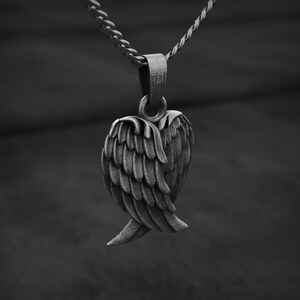 May include: A silver-toned pendant necklace featuring a detailed wing design. The pendant is suspended from a delicate chain, showcasing the intricate feather detailing. The necklace is a stylish accessory.