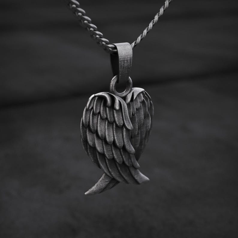 May include: A silver-toned pendant necklace featuring a detailed wing design. The pendant is suspended from a delicate chain, showcasing the intricate feather detailing. The necklace is a stylish accessory.