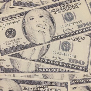 May include: A close-up of a stack of US $100 bills with a black and white drawing of a woman's face on each bill. The bills are arranged in a random pattern, with some overlapping. The text "UNITED STATES OF AMERICA" and "ONE HUNDRED DOLLARS" is visible on the bills.