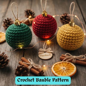 Könnte beinhalten: Drei handgefertigte Häkelkugeln in Grün, Rot und Gold, jede mit einer goldfarbenen Kappe und einer Schnurschlaufe. Die Kugeln sind auf einer rustikalen Holzoberfläche mit Tannenzapfen, Zimtstangen und getrockneten Orangenscheiben angeordnet. Der Text unten lautet "Crochet Bauble Pattern".
